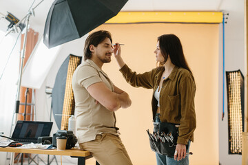 Make-up artist working during a photo session while preparing the look for the model
