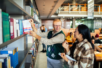 Professor discussing book with student in university library