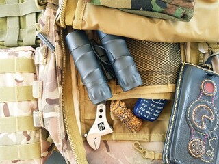 Binoculars and other military equipment on the soldier's bag.