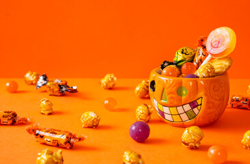 Fototapeta premium Halloween’s cup filled with Halloween treats. ハロウィンのお菓子でいっぱいになったハロウィン用のカップ