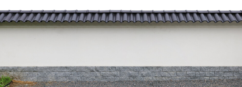 Long Japanese style fence with granite base and black tiles on top isolated
