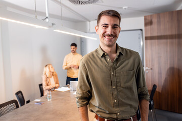 Portrait of smiling man standing in a meeting room looking at camera.