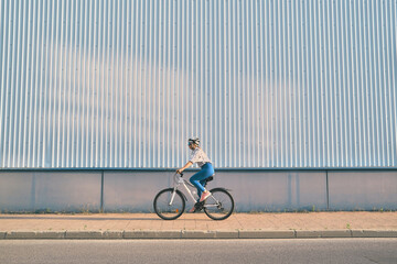 Athletic Woman in a Helmet Riding a Bicycle on the Street, Helmeted Woman Embraces Street Cycling...