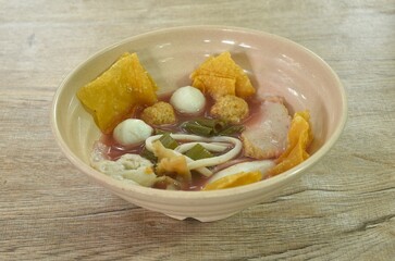 boiled fish and shrimp ball couple dumpling topping pickled cuttlefish in red soybean sauce soup topping fried crispy yellow dumpling flour on bowl