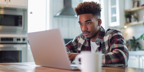 Focused young man working on laptop in modern kitchen