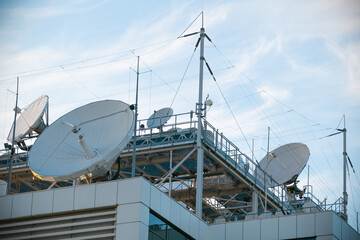 Large white satellite dish. Lots of antennas on the roof of the building.