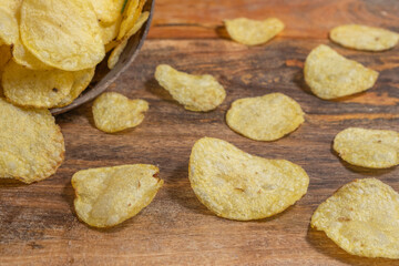 Homemade potato chips on wooden background.