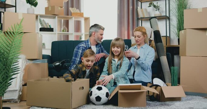 Family woman man and kids sitting on the floor among carton boxes in relocation day