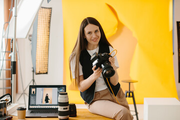 Young pretty female photographer looking at pictures on camera screen in her photo studio.