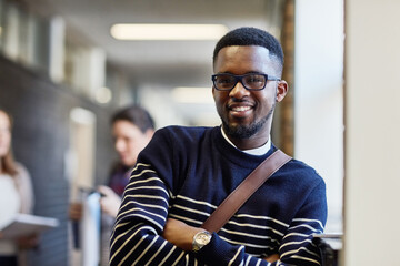 Naklejka premium Portrait, hallway and black man with backpack, education and proud of scholarship for college and learning. Corridor, university student and vision for knowledge, arms crossed and person in campus