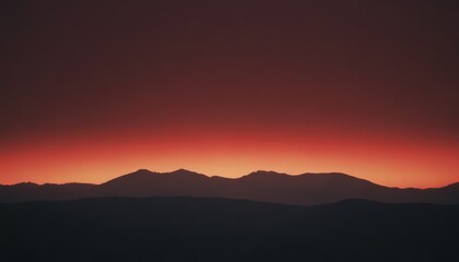 Silhouetted mountain range against a vibrant red sunset sky.