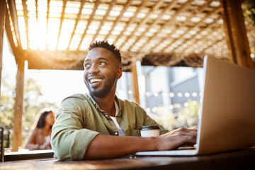 Black man, cafe and smile on laptop with coffee for remote work as lifestyle blogger in Kenya. Male...