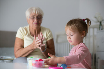 Grandmother and small girl making figures from play dough