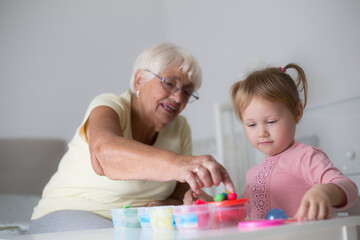 Grandmother and small girl making figures from play dough