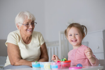 Grandmother and small girl making figures from play dough