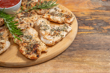 Grilled turkey chops, fresh rosemary on wooden background for barbecue.