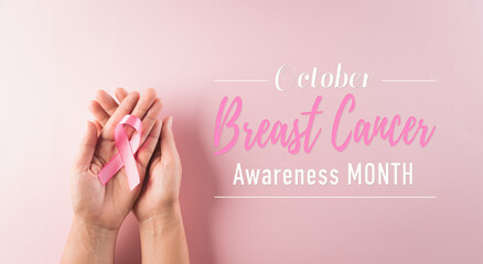Hands holding pink ribbon, Breast cancer awareness, symbolic bow color raising awareness on women's breast tumor. Healthcare and medical concept.