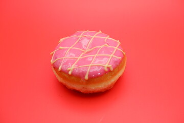 donut cake with pink chocolate glaze and white chocolate smeared in zigzag. donut cake isolated on red background.