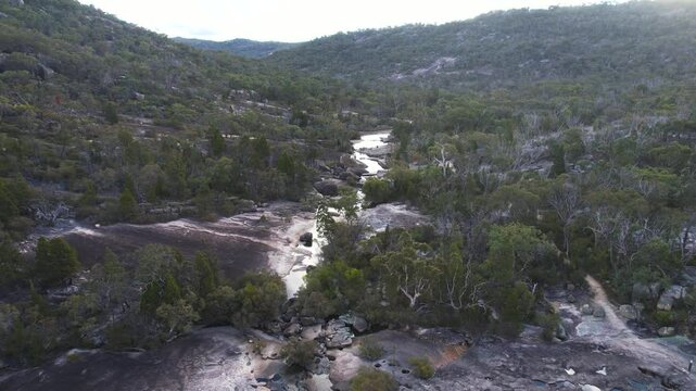 Aerial view of tranquil bald rock creek surrounded by rugged rock formations and lush forest, Girraween National Park, Queensland, Australia.