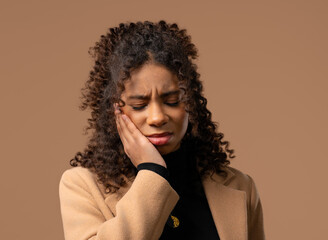 Young african woman with tooth pain on beige background.Toothache dental problem