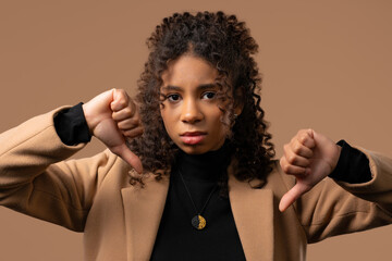 Young teen girl with dislike sign. Stylish african lady showing thumbs-down