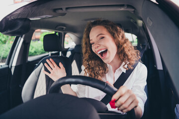 Photo of cheerful pretty lady dressed white shirt singing driving automobile enjoy traffic outdoors urban city street