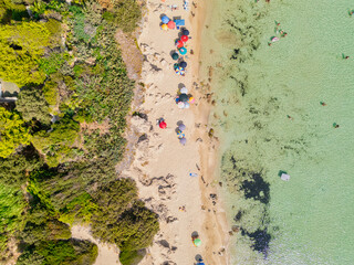 Vista aerea top down della spiaggia di San Pietro in Bevagna in estate. Dune, mare turchese e ombrelloni colorati. Puglia, Salento, Manduria, Italy