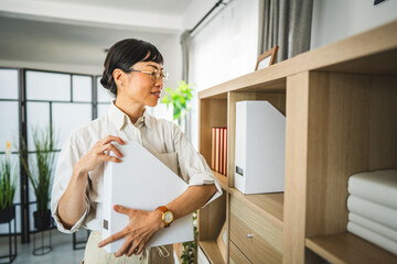 Mature japanese business woman organize folder on shelves at office