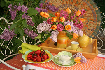 Afternoon tea still life outdoors with flowers on a tray and summer fruit on a plate