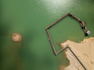 Aerial - drone view of Sand quarry with industrial structures and artificial lake.