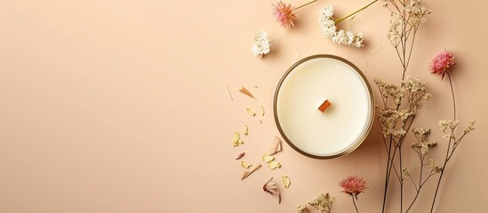Handmade candle made of soy and coconut wax in a glass container with a wooden wick and dried flowers set against a pastel beige background Flat lay top view copyspace