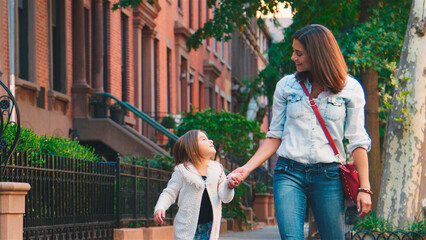 Family Shot With Mother And Daughter Walking Holding Hands Along Urban Street In New York City 