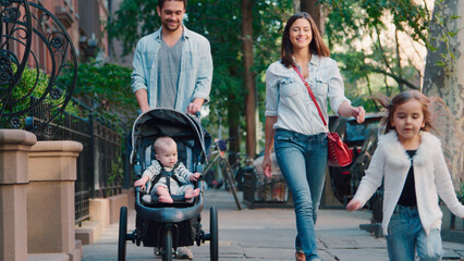 Family Day Out With Dad Pushing Baby In Buggy As They Walk Along Urban Street In New York City USA
