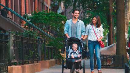 Family Day Out With Dad Pushing Baby In Buggy As They Walk Along Urban Street In New York City USA