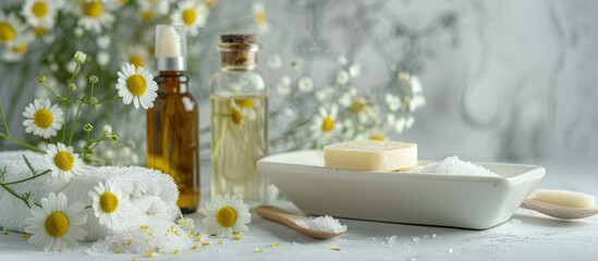 Chamomile spa Arrangement featuring chamomile flowers handmade soap a bottle of essential oil body cream scrub and sea salt on a white textured background Relaxing beauty treatments Copy space