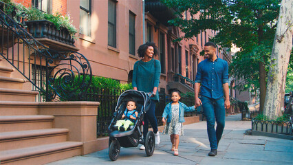 Family Day Out With Mum Pushing Baby In Buggy As They Walk Along Urban Street In New York City USA