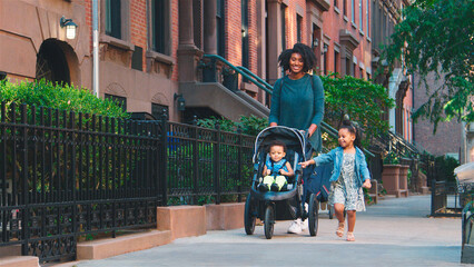 Family Day Out With Mum Pushing Baby In Buggy As They Walk Along Urban Street In New York City USA
