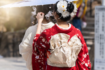 Obraz premium Young girl wearing Japanese kimono standing in front of Sensoji Temple in Tokyo, Japan. Kimono is a Japanese traditional garment. The word 