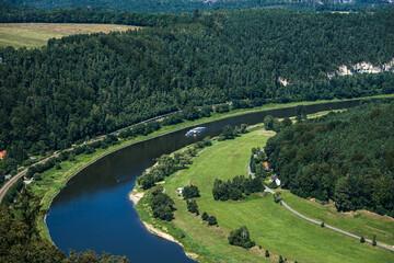 Aerial view of tourist ship cruising on winding river through forested landscape. Scenic travel destination, river cruise, nature exploration, eco-tourism.