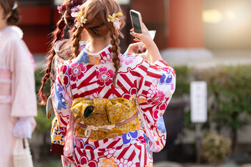 Young girl wearing Japanese kimono standing in front of Sensoji Temple in Tokyo, Japan. Kimono is a Japanese traditional garment. The word "kimono", which actually means a "thing to wear"