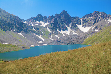 Obraz premium Beautiful natural landscape with high rocky mountains and crystal clear lake. Blue lagoon. Blue lake. Beautiful mountain with lake. Wild flowers