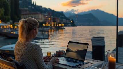 Woman using laptop by mountain lake, digital nomad working in scenic autumn landscape, remote work and travel lifestyle concept