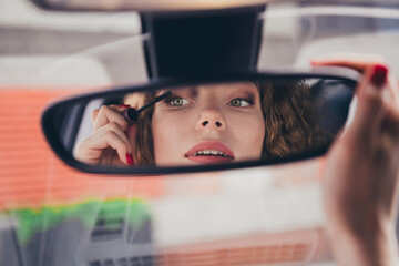 Photo of shiny attractive lady driver dressed white shirt smiling riding car applying mascara outdoors urban city street