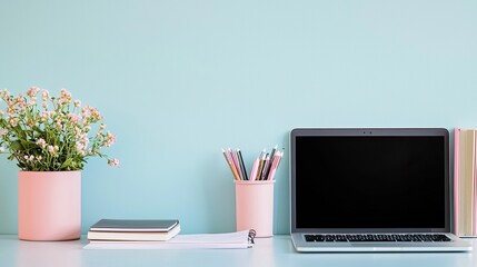 A neatly organized desk with stationery, a laptop, and a potted plant arranged for productivity.
