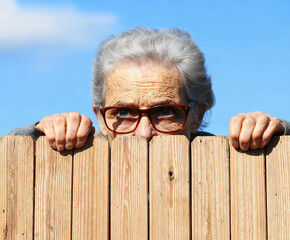 Silent Observer. An Old Woman Peering Over the Fence