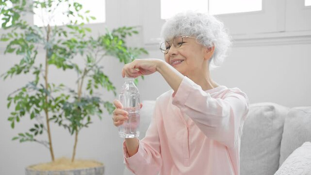 ペットボトルの水を飲むシニア女性	

