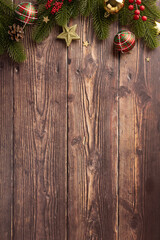 Top vertical view of Christmas decorations on a rustic wooden background, featuring festive ornaments, greenery, and a cozy holiday atmosphere