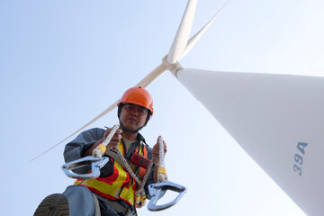 worker in Personal Protective Equipment work with wind turbine farm.  people in Safety Harness work on wind mill.