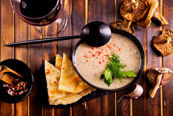 Bowl of creamy mushroom soup, sliced mushrooms and parsley with bread