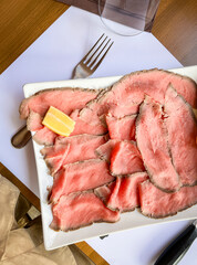 Roast beef - raw meat on a plate and a lemon